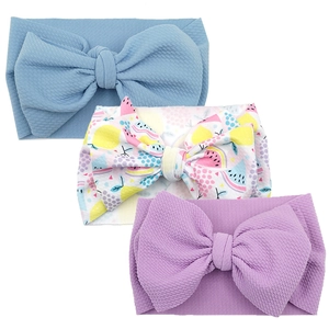 Three-piece baby headband set featuring large bows in blue, lilac, and fruit prints