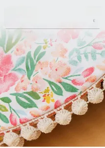 Détail du bavoir bébé floral montrant la texture gaze respirante et la bordure pompon
