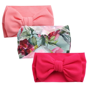 Detailed waffle texture of three baby headbands with pink and floral large bows