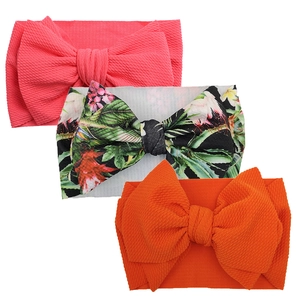 Detail of three baby headbands with large bows in pink, floral, and orange textured fabric