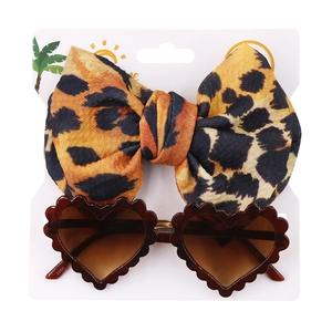 Detail view of heart-shaped sunglasses and leopard print bow headband set on display card