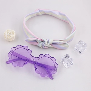 Dettaglio di occhiali da sole a fiore viola e fascia con fiocco a righe per bambini