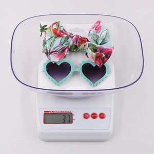 Kids heart sunglasses and floral bow headband set displayed on white scale