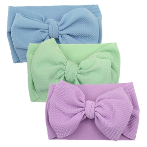 Close-up of three pieces waffle knit baby headbands with large bows in pastel colors