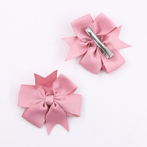 Detalle de horquillas con lazo rosa que muestra el estilo frontal y clips de cocodrilo plata