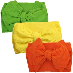 Three-piece baby bow headband set in green, yellow, and orange ribbed knit fabric