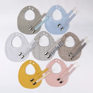 Set of seven cotton baby bibs and pacifier clips in various soft pastel colors