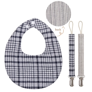 Detail of baby bib and pacifier clip set featuring blue plaid and striped cotton fabric
