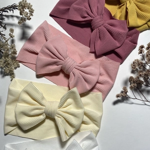 Detailed texture of ribbed knit baby headbands with large bows in multiple soft colors