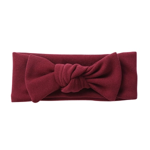 Detail of burgundy baby headband with large cashmere-like bow and elastic knit texture