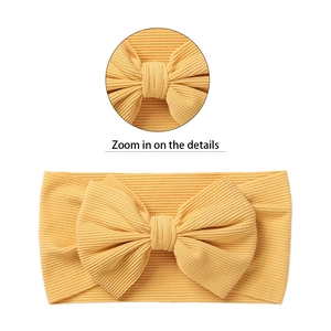 Elastic mustard yellow ribbed knit baby headband with a large 3D decorative bow accent