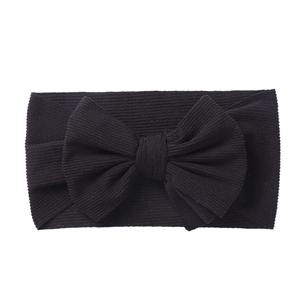 Detail of black elastic knitted baby headband featuring a large 3D ribbed fabric bow