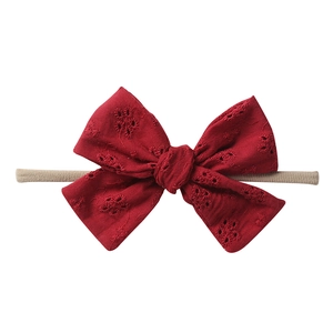 Detailed eyelet embroidery on dark red cotton bow headband with soft nylon cord