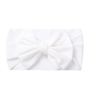 Detail view of a soft white knitted baby headband with a large handmade bow decoration