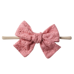 Close-up of pink cotton bow with floral embroidery on soft nylon baby headband