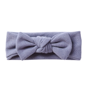 Detail of soft lavender knitted elastic baby headband with a large bow on white background