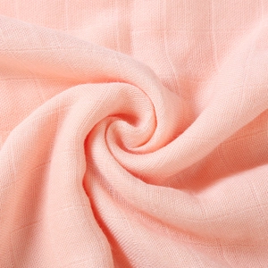 Close-up of soft pink bamboo cotton muslin fabric with breathable mesh texture for infants
