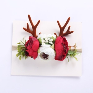 Close-up of baby reindeer headband with festive artificial flowers and plush antlers