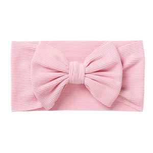 Detail of baby pink ribbed knit headband featuring a large soft bow for infants