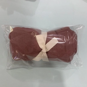 Detail view of terracotta bamboo cotton swaddle with leaf embroidery and ribbon bow