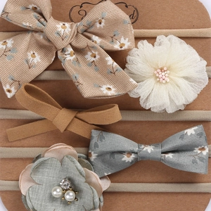 Detail view of five assorted elastic nylon headbands with floral bows and lace for infants