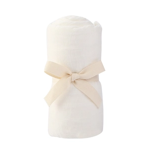 Macro shot of a white bamboo cotton muslin swaddle roll tied with a beige herringbone ribbon