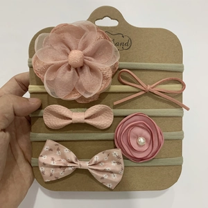 Detail of five-piece baby headband set featuring pink bows and floral mesh on kraft card