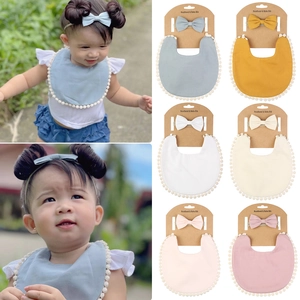 Détail de l'ensemble bavoir boho et bandeau bébé avec bordure pompon en six couleurs douces