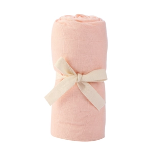 Macro shot of rolled pink-orange bamboo cotton baby swaddle with white ribbon tie