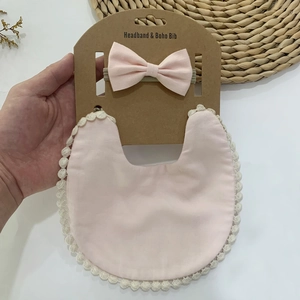 Détail d'un bavoir bébé rose en coton de bambou avec dentelle et bandeau à nœud assorti