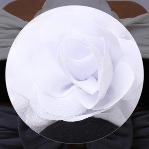Detailed view of handmade 3D white fabric rose headband accessory on cardboard display