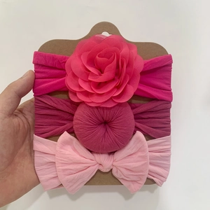 Three-piece baby nylon headband set featuring pink flowers and bows on a display card