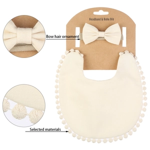 Détail ensemble de bavoir bébé avec pompons doux et bandeau assorti en blanc crème