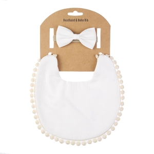 Détail du bavoir bébé boho blanc avec pompons et bandeau à nœud sur support cartonné