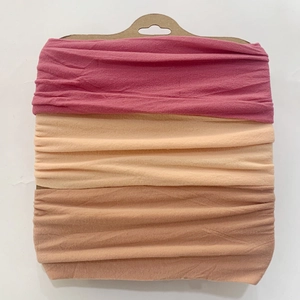 Detailed view of three elastic baby headbands in pink, beige, and tan on a kraft card