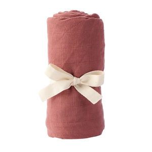 Detail of soft bamboo cotton baby swaddle blanket in brick red with white ribbon bow