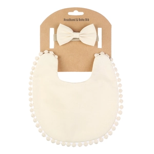 Détail de l'ensemble bandeau bébé et bavoir boho avec bordure pompon sur carton