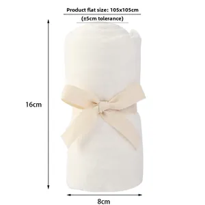 Folded white bamboo cotton baby swaddle blanket with decorative ribbon tie and texture details
