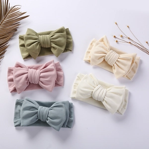 Flat lay of five soft ribbed cotton baby bow headbands in various pastel colors