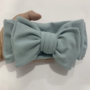 Detailed close-up of ribbed texture and large bow on a soft baby headband in light blue