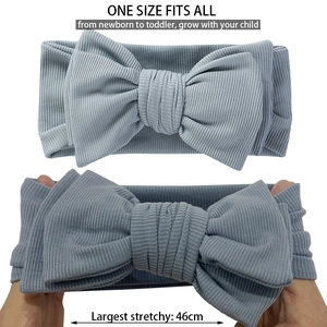 Detailed elastic stretch test of rib-knit baby headband with large bow in dusty blue