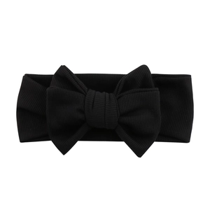 Close-up of black ribbed knit baby headband featuring a large soft decorative bow