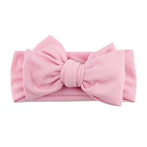 Close-up of pink ribbed cotton baby headband featuring a large soft bow and elastic texture