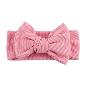 Detailed view of soft pink ribbed knit baby headband with a large decorative bow