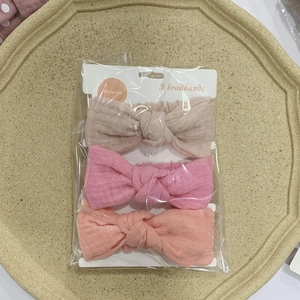 Detailed set of three muslin cotton baby bow headbands in shades of pink on display tray