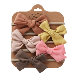 Detail of 5-piece handmade bow headbands on display card with soft cotton-linen texture