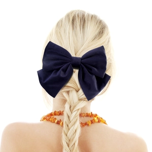 Detail of a large navy blue velvet bow hair clip shown on blonde braided hair