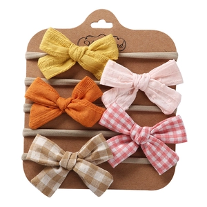 Close-up of five handmade cotton bow headbands displayed on a craft paper card