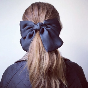 Close-up back view of a large black satin velvet bow hair clip worn on a ponytail