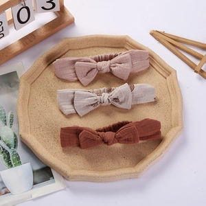 Three-piece baby bow headband set in soft crepe cotton fabric on wooden tray decor